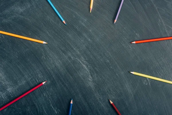 Top view of circle frame of color pencils on green chalkboard — Stock Photo