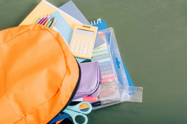 Vue grand angle du sac à dos jaune avec fournitures scolaires sur tableau vert — Photo de stock