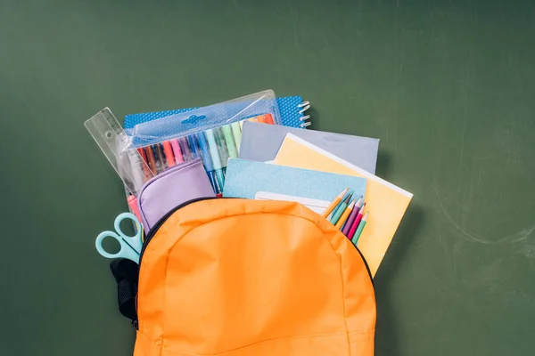 Vista superior da mochila escolar com artigos de papelaria em quadro-negro verde — Fotografia de Stock