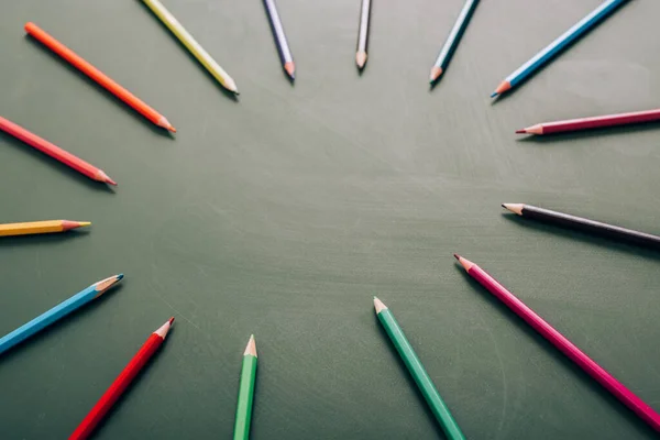 Mise au point sélective du cadre circulaire des crayons de couleur sur le tableau vert, vue grand angle — Photo de stock