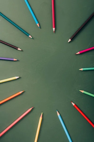 Вид сверху пустой рамки цветных карандашей на зеленой доске — стоковое фото