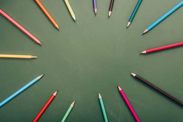 Top view of circle frame of multicolored pencils on green chalkboard with copy space — Stock Photo