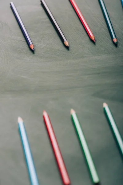 Selective focus of multicolored pencils on green chalkboard, high angle view — Stock Photo