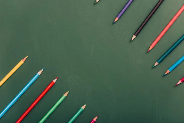 Top view of multicolored pencils on green chalkboard — Stock Photo