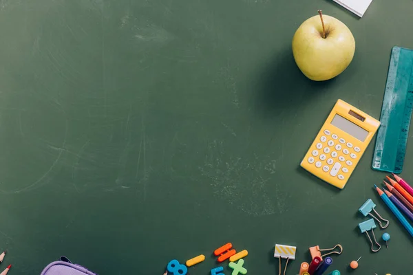 Vista superior de maçã madura e calculadora perto de material escolar no quadro verde — Fotografia de Stock