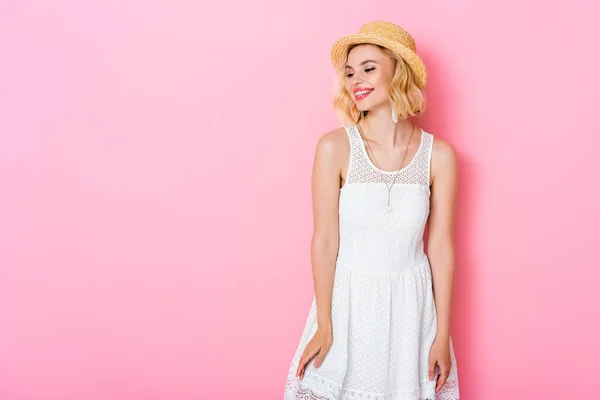 Mulher de chapéu de palha e vestido branco em pé sobre rosa — Fotografia de Stock