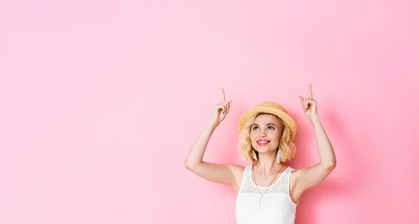 Horizontal image of woman in straw hat pointing with fingers and looking up on pink — Stock Photo