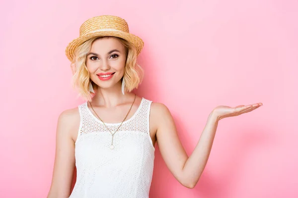 Frau mit Strohhut und Kleid zeigt mit der Hand auf rosa — Stockfoto