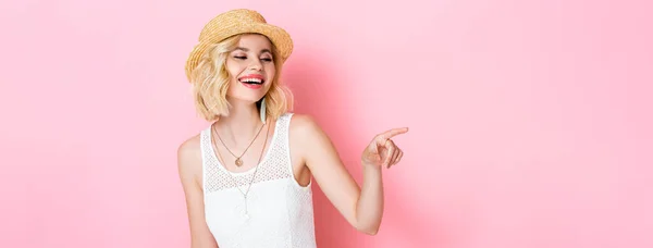 Imagen horizontal de la mujer en sombrero de paja riendo y señalando con el dedo en rosa - foto de stock