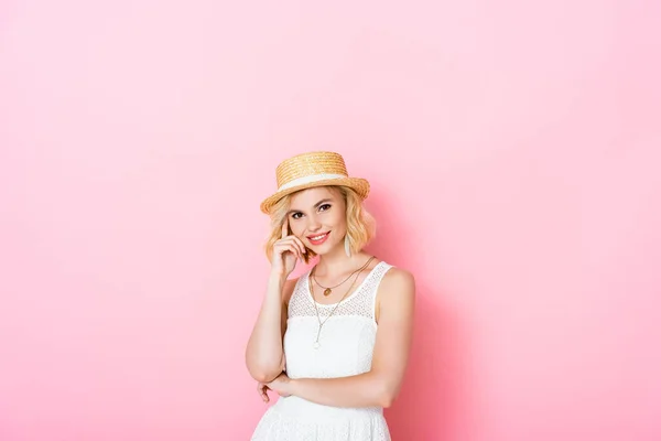 Young woman in straw hat looking at camera on pink — Stock Photo