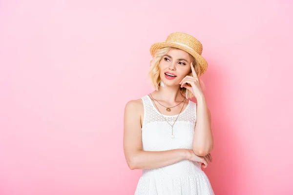 Pensive young woman in straw hat thinking on pink — Stock Photo