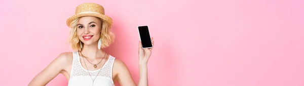 Plano panorámico de mujer en sombrero de paja sosteniendo teléfono inteligente con pantalla en blanco en rosa - foto de stock