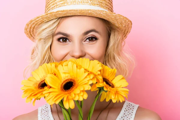 Jeune femme en chapeau de paille couvrant le visage avec des fleurs jaunes sur rose — Photo de stock