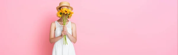 Site web tête de jeune femme en chapeau de paille et robe blanche couvrant visage avec des fleurs jaunes sur rose — Photo de stock