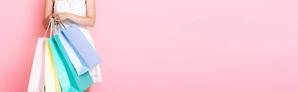 Panoramic crop of young woman holding shopping bags on pink — Stock Photo
