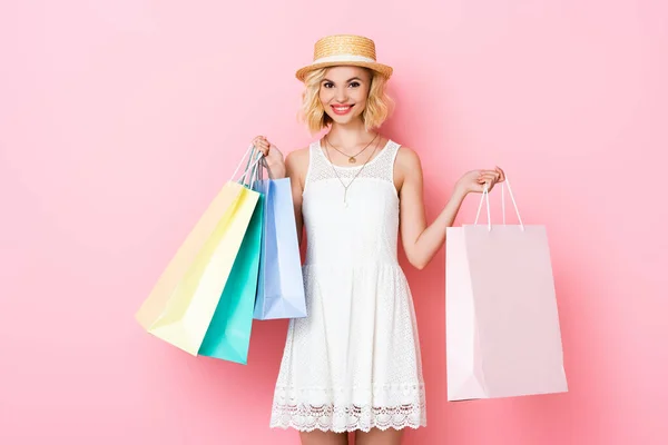 Junge Frau im weißen Kleid mit Einkaufstaschen auf rosa — Stockfoto