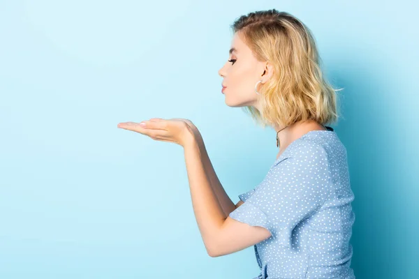 Side view of woman sending blowing kiss on blue — Stock Photo