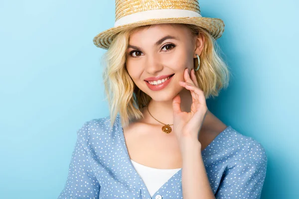 Junge Frau mit Strohhut blickt in Kamera auf blau — Stockfoto