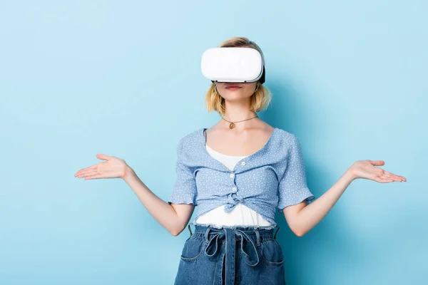 Junge Frau im Virtual-Reality-Headset gestikuliert auf blau — Stockfoto