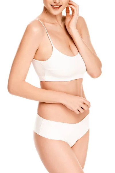 Partial view of young woman in top and panties standing and touching face isolated on white — Stock Photo