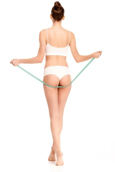 Visão traseira da mulher segurando fita métrica perto de nádegas isoladas em branco — Fotografia de Stock