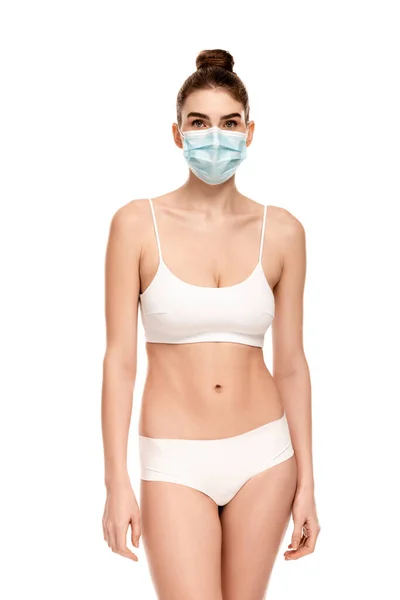 Jeune femme en masque médical, haut et culotte isolé sur blanc — Stock Photo