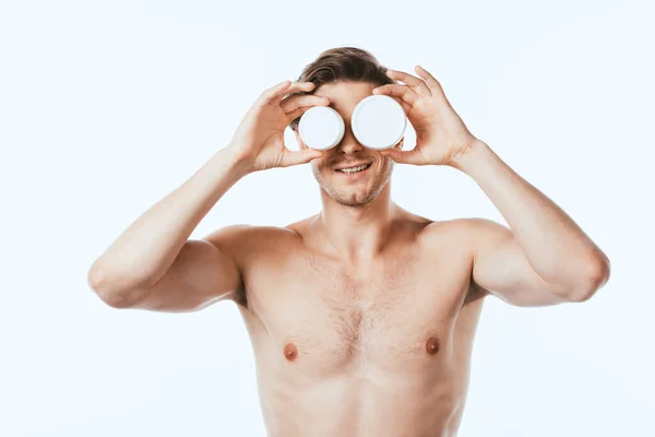Мужчина без рубашки с банками косметических кремов, изолированных на белом — стоковое фото