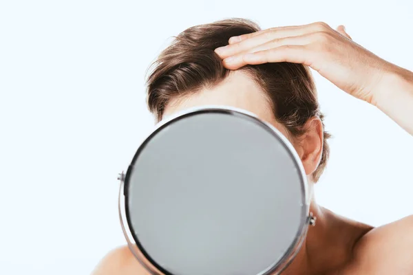 Мужчина без рубашки касается волос возле зеркала, изолированного на белом — стоковое фото