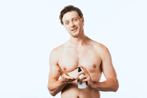 Homme torse nu tenant une bouteille de lotion et regardant la caméra isolée sur blanc — Photo de stock