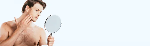 Tiro panorâmico de homem muscular tocando bochecha enquanto segurando espelho isolado no branco — Fotografia de Stock