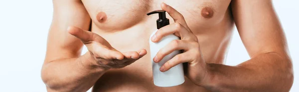Panoramic shot of muscular man holding bottle of lotion isolated on white — Stock Photo