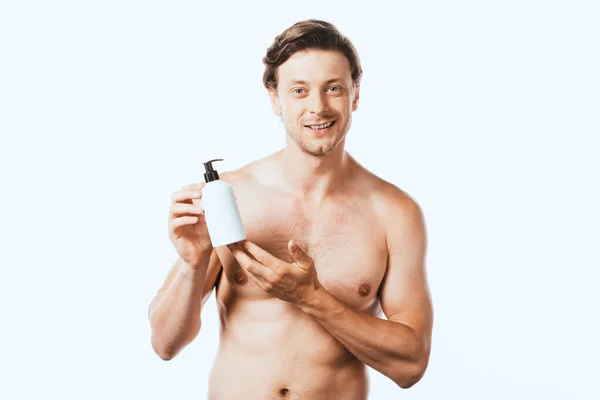 Junger Mann hält eine Flasche Lotion in der Hand und blickt isoliert in die Kamera — Stockfoto