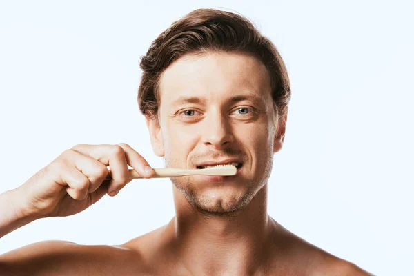 Shirtless man looking at camera while brushing teeth isolated on white — Stock Photo