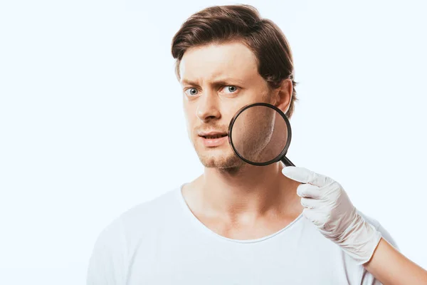 Dermatologe hält Lupe in der Nähe nachdenklicher Mann isoliert auf weiß — Stockfoto