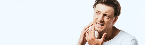 Panoramic orientation of displeased man touching skin on cheek isolated on white — Stock Photo