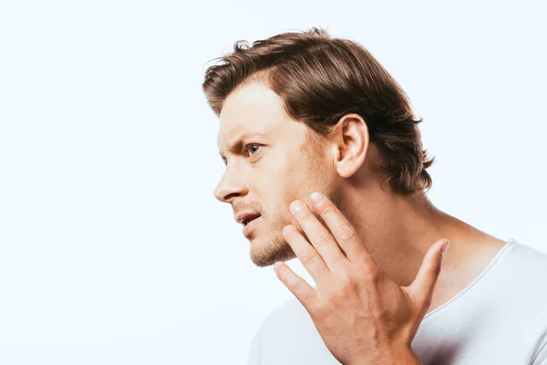 Concentrated man looking away while touching cheek isolated on white — Stock Photo