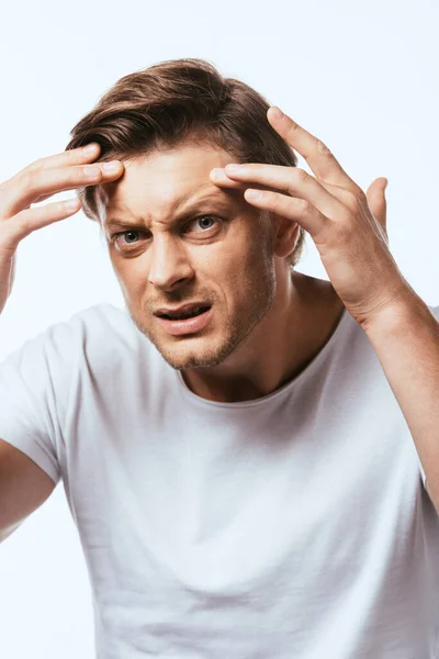 Besorgter Mann berührt Haut auf der Stirn und blickt in Kamera isoliert auf Weiß — Stockfoto