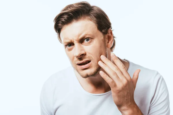 Worried man looking at camera and touching skin on cheek isolated on white — Stock Photo