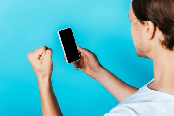 Mann zeigt Yah-Geste und hält Smartphone mit leerem Bildschirm auf blauem Hintergrund — Stockfoto