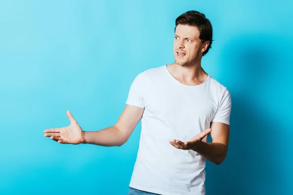 Aggressive man pointing with hands while looking away on blue background — Stock Photo