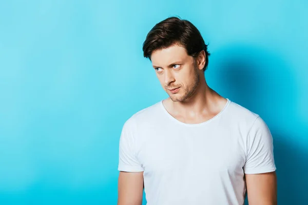 Homme confiant en t-shirt blanc regardant loin sur fond bleu — Photo de stock