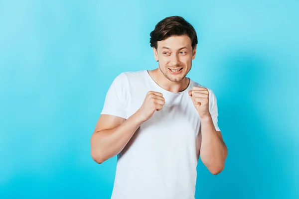 Uomo spaventato con le mani in pugno guardando lontano su sfondo blu — Foto stock