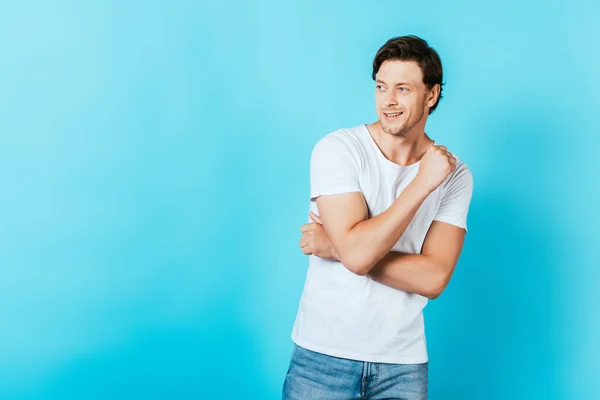 Jeune homme en t-shirt blanc regardant loin sur fond bleu — Photo de stock