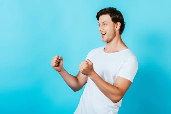 Junger Mann im weißen T-Shirt zeigt Yah-Geste auf blauem Hintergrund — Stockfoto
