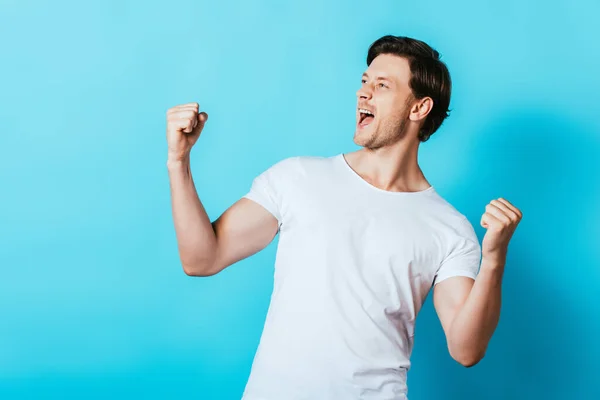 Junger Mann im weißen T-Shirt zeigt Ja-Geste auf blauem Hintergrund — Stockfoto