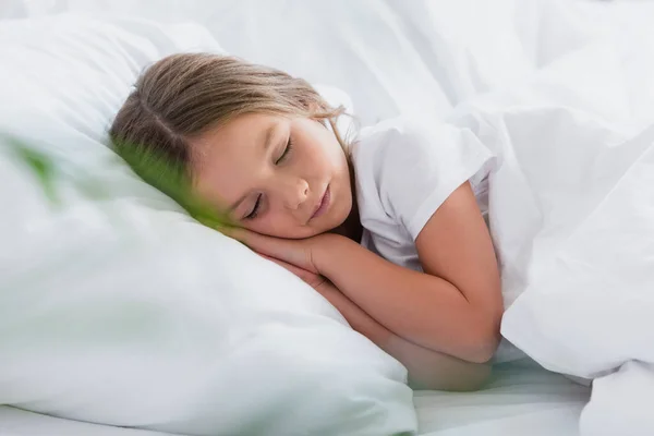 Enfoque selectivo de la niña durmiendo mientras está acostado en la ropa de cama blanca - foto de stock