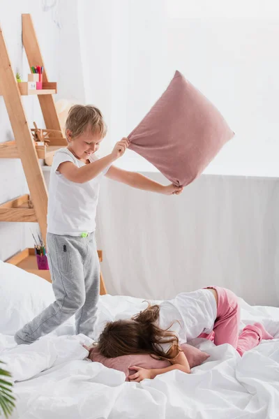 Schwester und Bruder haben Spaß beim Kampf mit Kissen im Schlafzimmer — Stockfoto