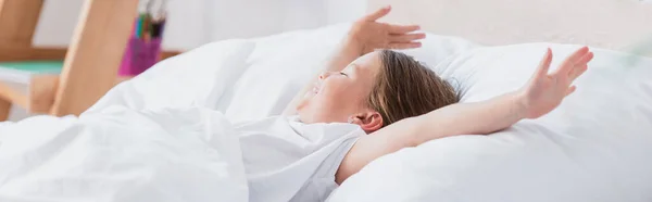 Horizontal image of awakened girl stretching while lying in bed — Stock Photo