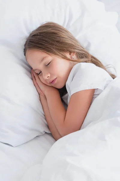 Child sleeping on white bedding in morning — Stock Photo