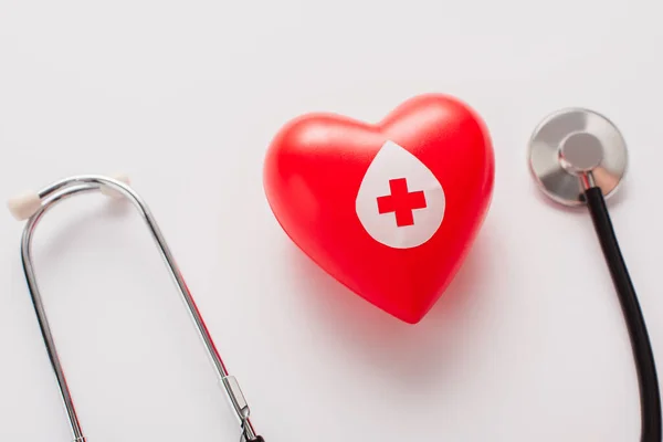 Vista superior del corazón rojo y el estetoscopio en blanco, concepto de donación de sangre - foto de stock